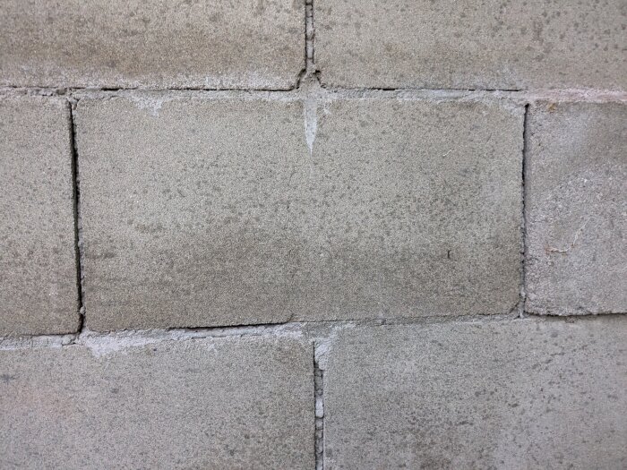 Betongvägg av ihåliga murblock, eventuellt fyllda med sågspån. Blocken är staplade i varandra med synliga fogar.