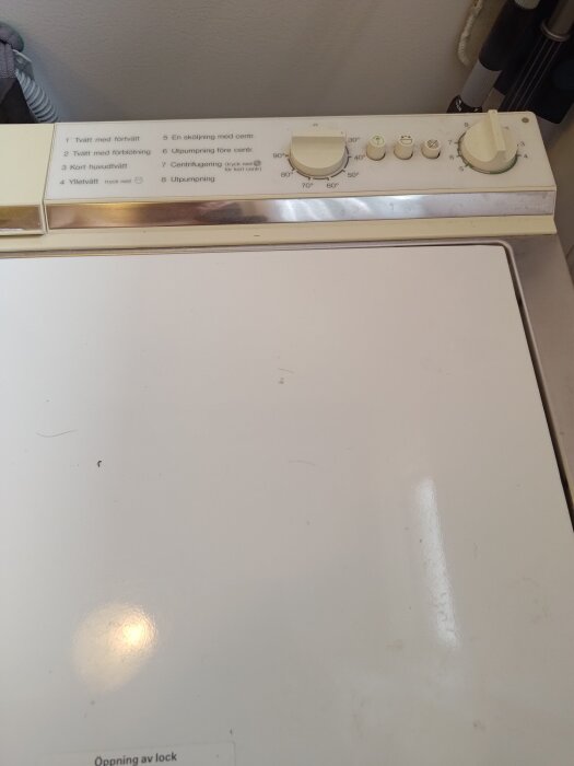 Gammal tvättmaskin med kontrollpanel och vridknappar för programinställningar.