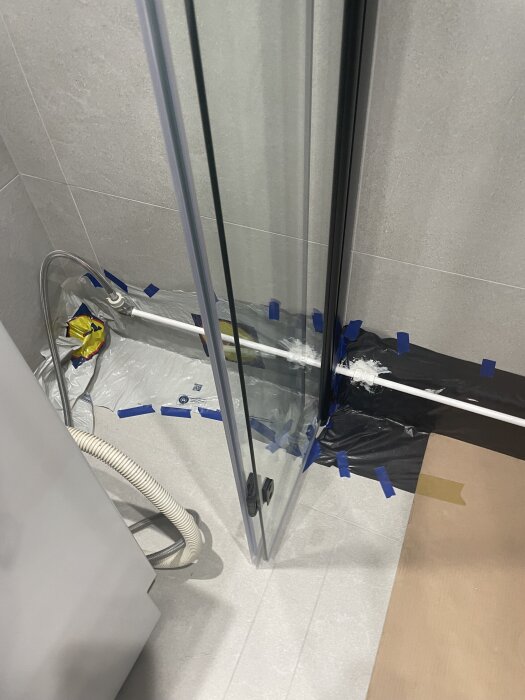 Målade rör i badrummet med mattsvart lackfärg, omgivna av skyddsplast och tejp.