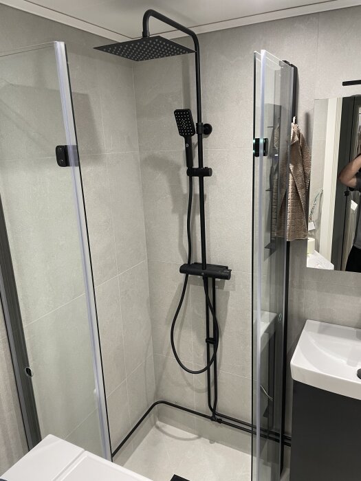 Duschhörna med nyrenoverade svarta rör och duschset i ett badrum. Rören målade med elementfärg och mattsvart lackfärg.