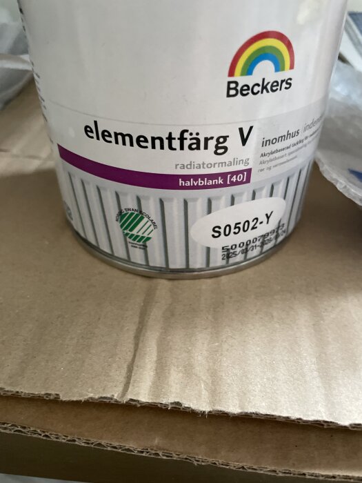 Burk med Beckers elementfärg V, halvblank, stående på kartong, använd för att måla rören i ett renoveringsprojekt.