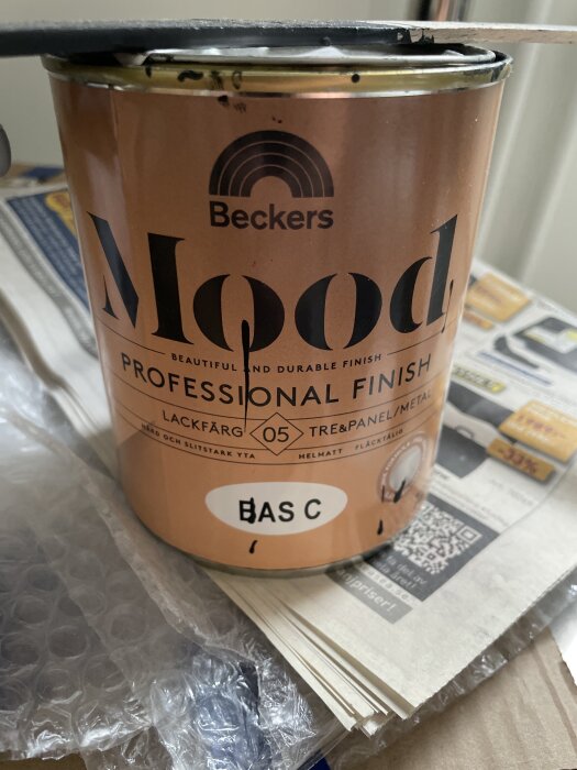 En burk med Beckers Mood lackfärg, bas C, för trä och metall, med en pensel på toppen.