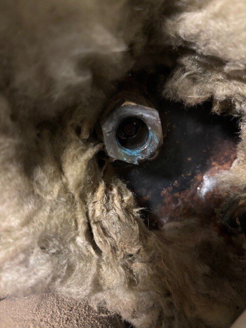 Ventil med fjädrande pigg bakom isolering i en Biomatic 20+, delvis täckt av korrosion, som inte tätar ordentligt vilket orsakar vattenläckage.