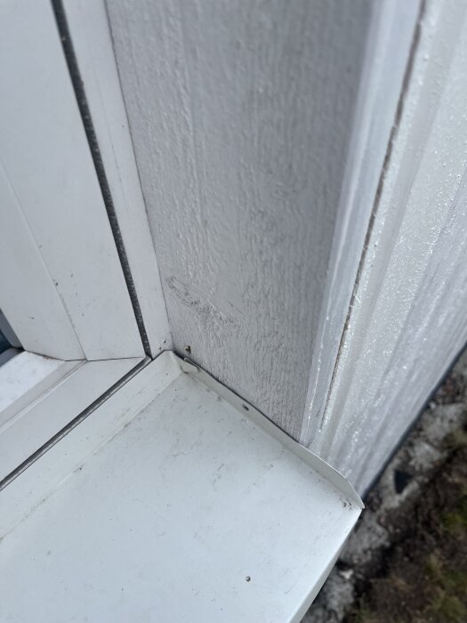 Närbild av fönsterhörn med fönsterbleck monterat utan sidofoder, visa befintlig montering innan byte till nya fönsterbleck i nybygge.
