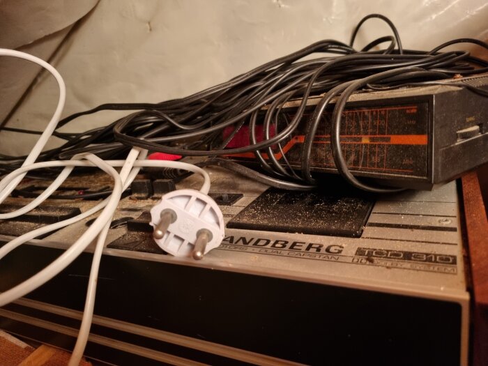 Rund ojordad stickpropp, delvis modifierad, på en gammal Tandberg-stereo från 1975/76, omgivet av kablar.