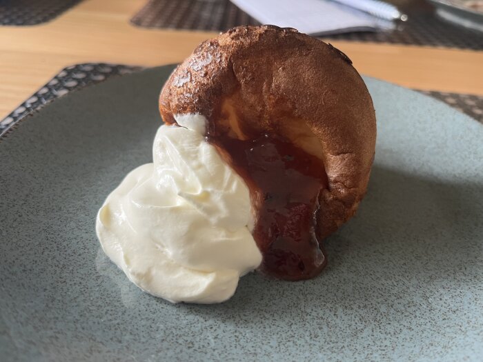 Pannkaksmuffin serverad med vispad grädde och hemgjord sylt på en tallrik.