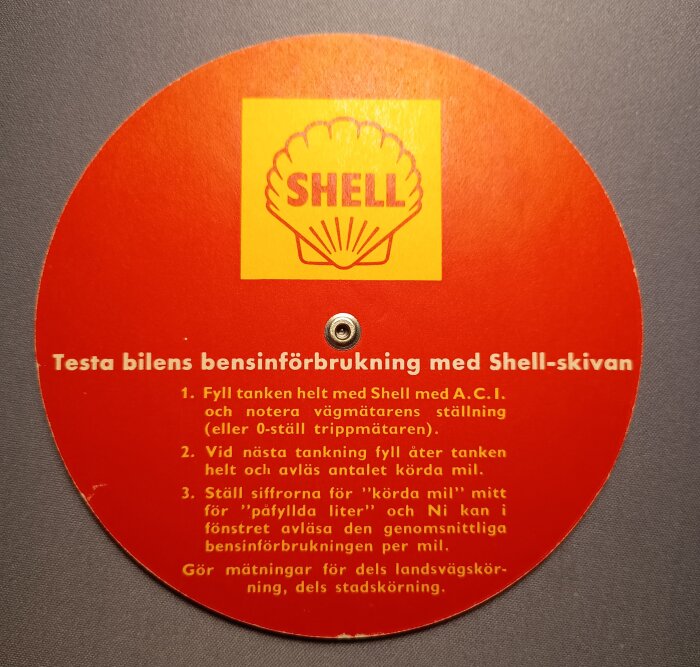 Reklamskiva från Shell med instruktionssteg för att beräkna bilens bensinförbrukning, inklusive företagets logotyp.