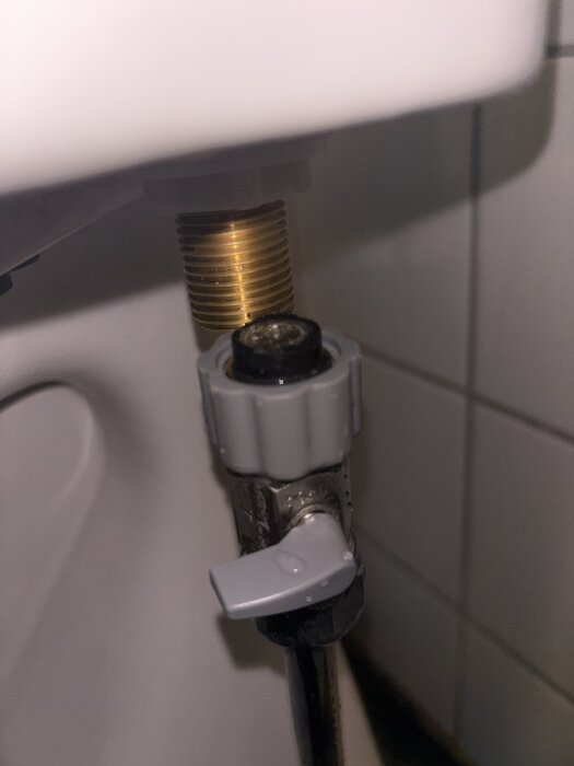 Ballofix-anslutning under toalettcistern med synlig flottör och gummipackning. Eventuellt läckage vid kopplingens tätning.