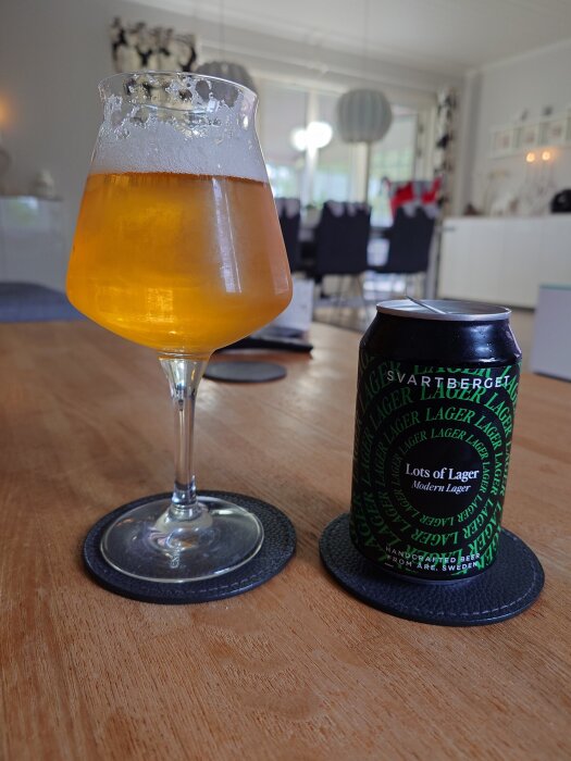 Ölglas och en burk med "Lots of Lager" från Svartbergets bryggeri på ett bord i ett vardagsrum.