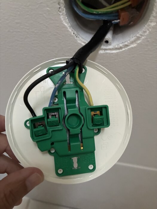 Takarmaturlock från Schneider Electric med synliga kablar kopplade till gröna kontakter.
