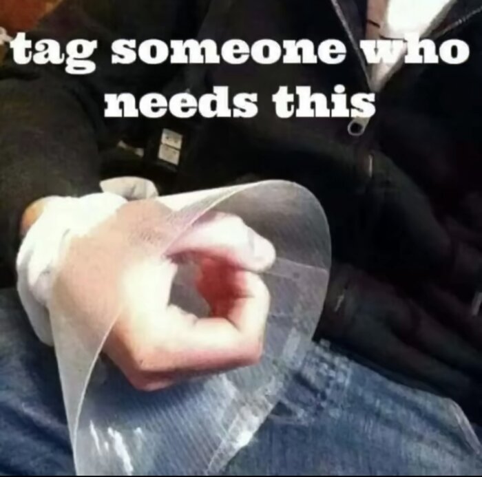En person gör cirkeltecknet med handen under ett böjt genomskinligt papper med texten "tag someone who needs this".