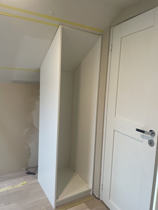 Inbyggd snedskuren garderobsstomme under sluttande tak i renoverat rum.