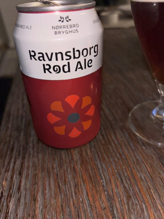 Burk med Ravnsborg Rød Ale från Nørrebro Bryghus på ett träbord.