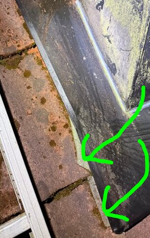 Takplåt vid murad vägg med synlig takpapp och gröna pilar som pekar mot pappen.