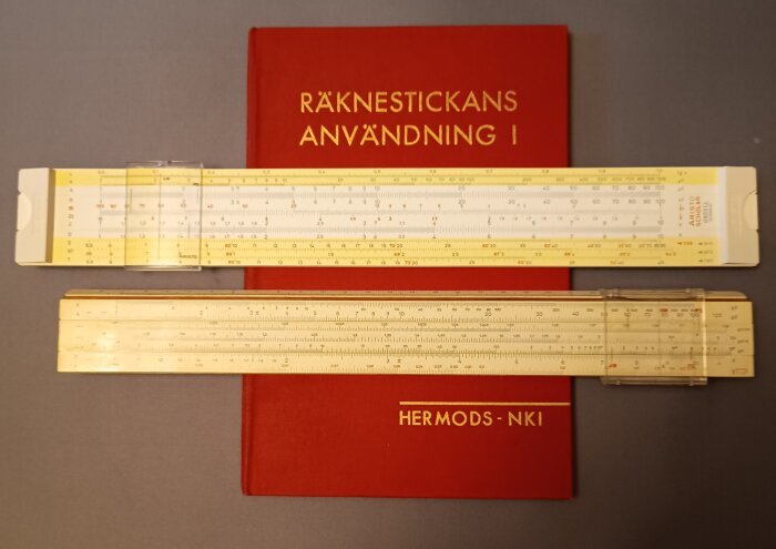 Räknestickor placerade ovanpå en röd kursbok med texten "Räknestickans användning I" och "Hermods-NKI".