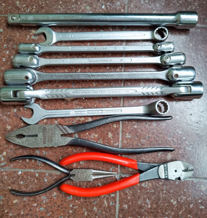Verktyg på golv: skiftnycklar, hylsnycklar, polygrip och avbitare från en loppisfynd för hundra kronor. Några är oanvända.