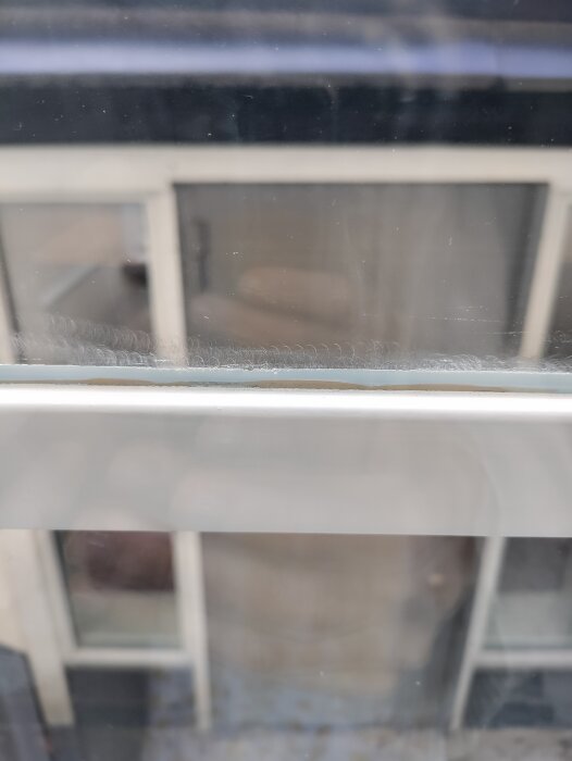 Fönster med tydliga slipmärken; visar oregelbundna cirklar och skador efter ommålning.