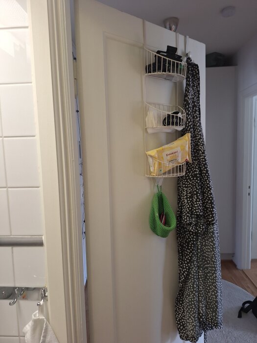 Öppen innedörr med hängande förvaring och mönstrad klädhängare, synlig från vänster sida.