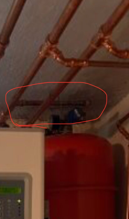 Rörsystem med manuell påfyllning markerad i rött, kopparrör synliga under tak.