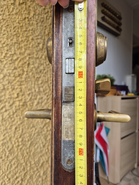 Dörrlås med mätsnöre visar måttet på 21 cm, med trä och metall detaljer synliga.