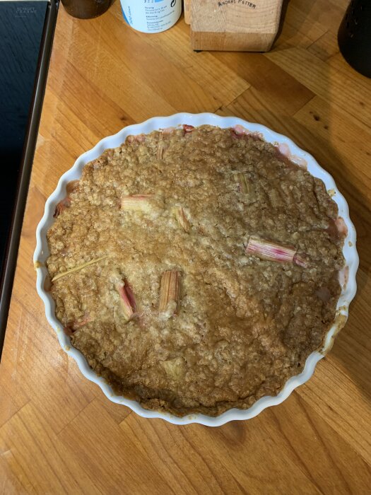 En nybakad rabarberpaj i en rund form på en träbänk.