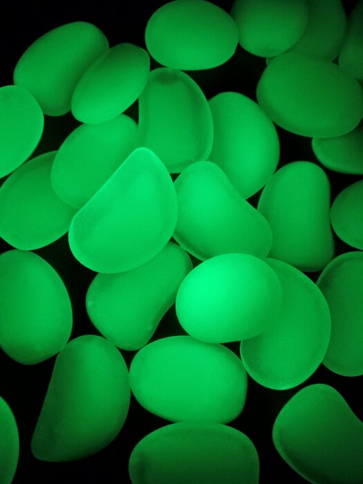 Självlysande dekorstenar i grönt ljus mot svart bakgrund.