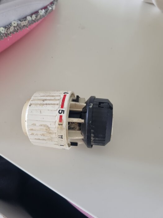 Gamla termostat för element liggande på ett bord med justeringssiffror och en röd indikeringslinje.