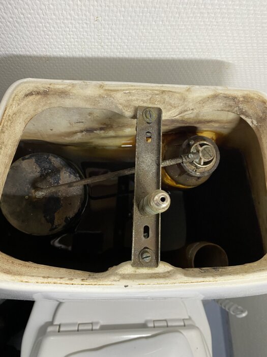 Gammal IFÖ toalettcistern med synliga insidan och slitna delar, söker reservdelar eller reparationsråd för läckage.