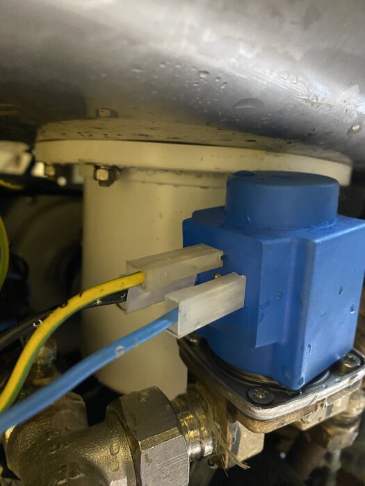 Blå ventil med anslutna kablar, monterad på ett rör i uppvärmnings- eller vattenanläggning.