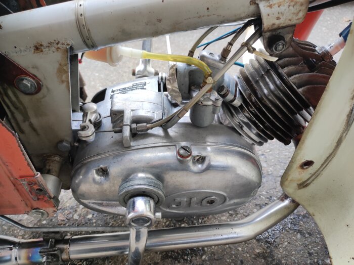 Mopedmotor från 1959, nyligen restaurerad med synlig förgasare och metallkomponenter, monterad på mopedram.