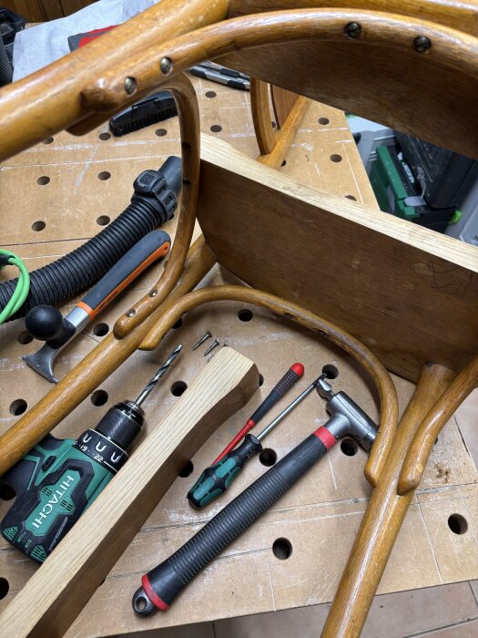 Reparerad Televerksstol med verktyg och trädetaljer på arbetsbänk.