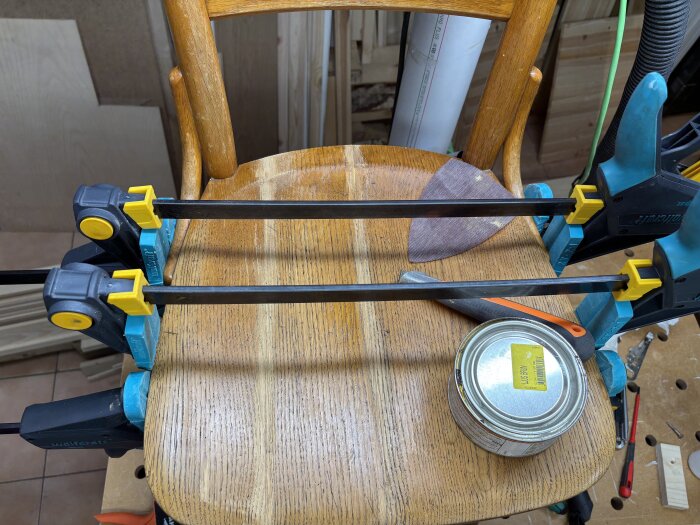Trästol med limmade delar, fastspända med tvingar; burk med shellack, kniv och sandpapper ligger på sitsen.