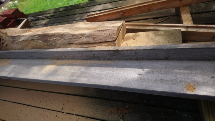 Hyvlade och sågade träplankor ligger på en trall, omgivet av sågspån.