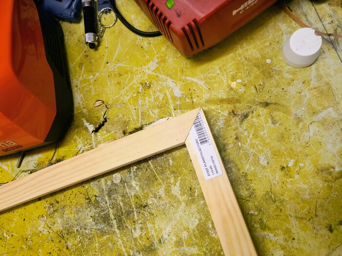 Träram för myggfönsterkonstruktion på arbetsbänk med verktyg; närbild på en hörndel med etikett.