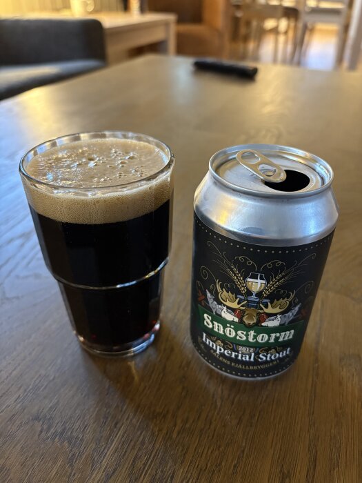 Öppen burk och glas med mörk imperial stout-öl på ett bord.