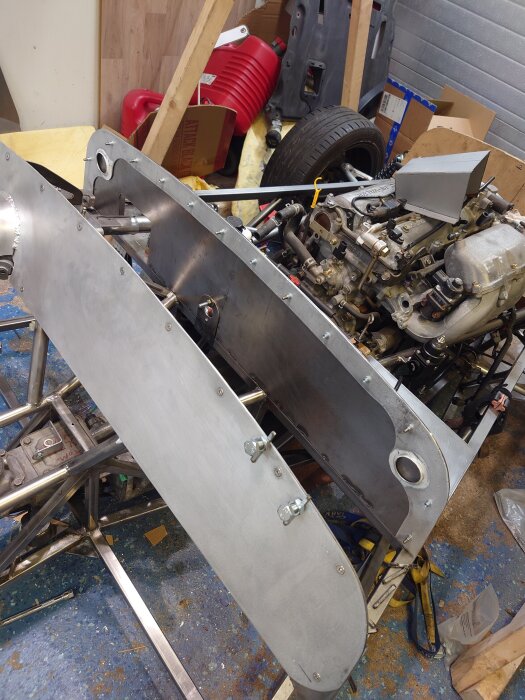 Plåtarbete på en bils scuttle, med metallpaneler och en motor synlig i verkstadsmiljö.