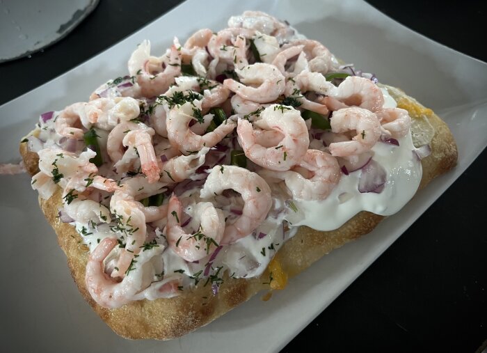 Pinsa med räkor, gräddfil, rödlök, padrone och dill på färskost och mozzarella.