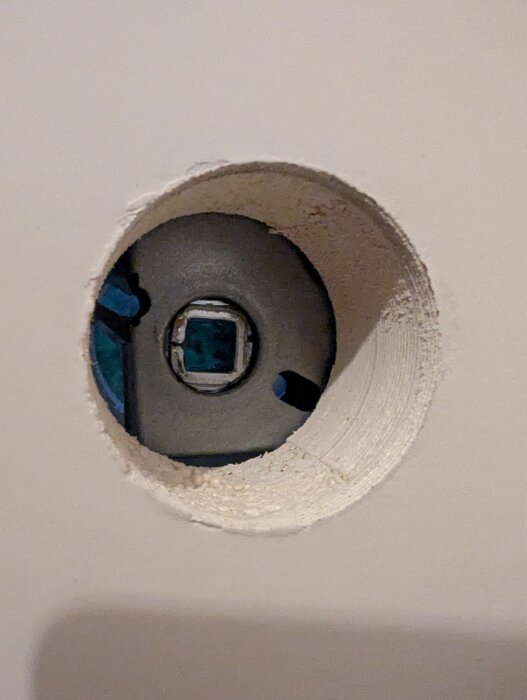 Fyrkantigt hål i dörrens låskista med en något vinklad öppning.