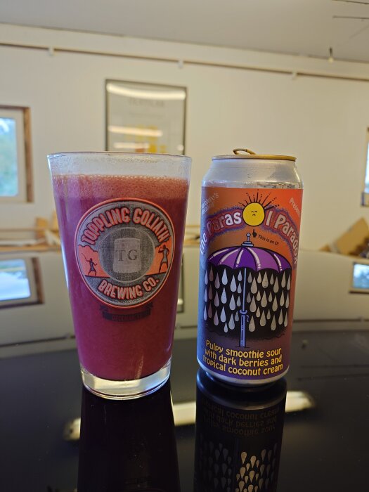 Ett glas med mörkröd smoothie och en burk med etikett föreställande ett paraply och text om bär och kokos.