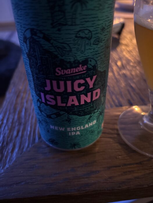 Burk med "Svaneke Juicy Island New England IPA" på ett bord, glas med öl bredvid.