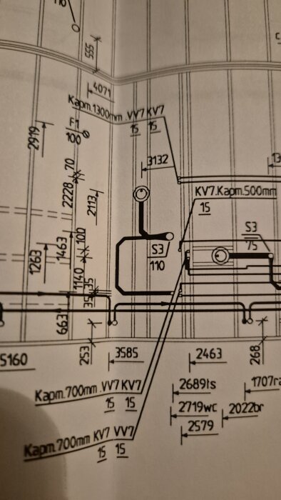 Byggritning med detaljerade mått och märkningar för ett badrum med fokus på rör och brunnsplacering.