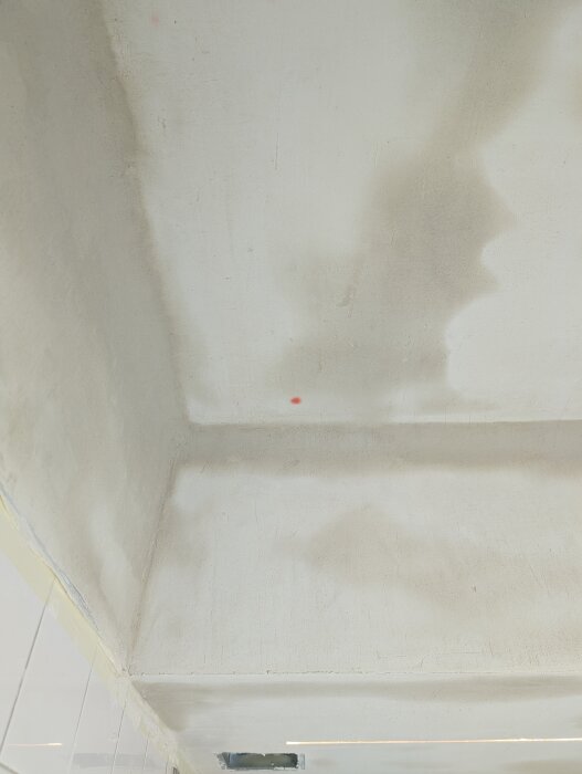 A ceiling with drywall and plaster, displaying a red spot near a screw location. Other screws are unaffected, raising questions on the cause of the spot.