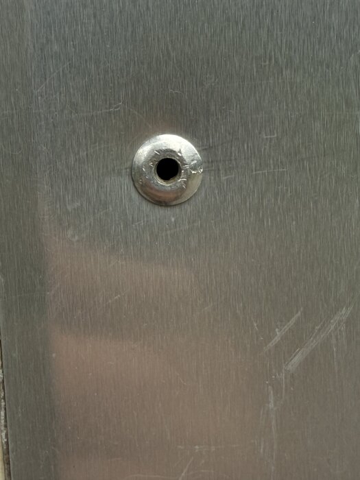 Metallpanel med en nitning eller liknande fastsättning visas närbild.