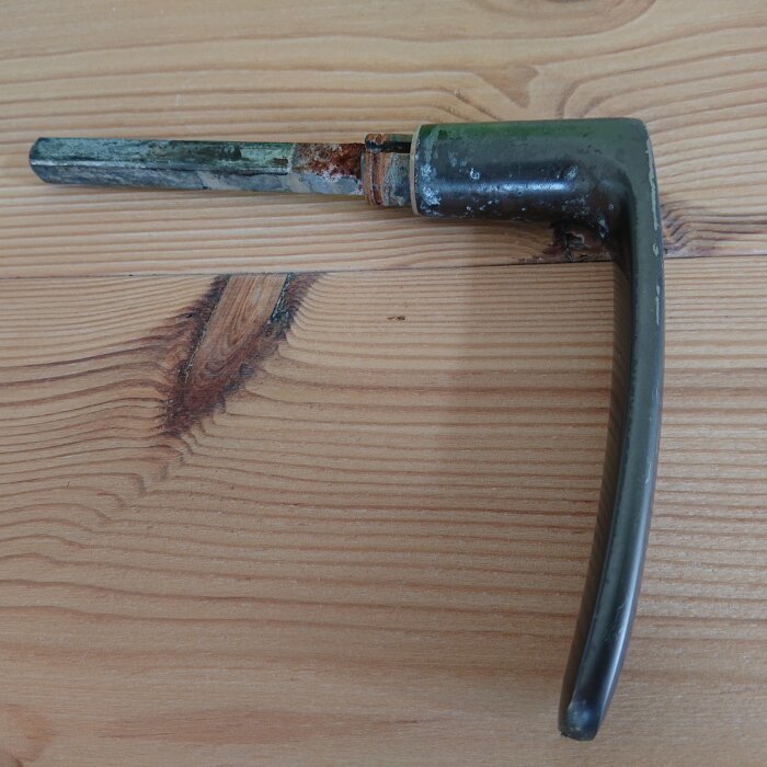 Rostig var-formad skiftnyckel placerad på ett träbord, synligt slitage och färgavskavningar.