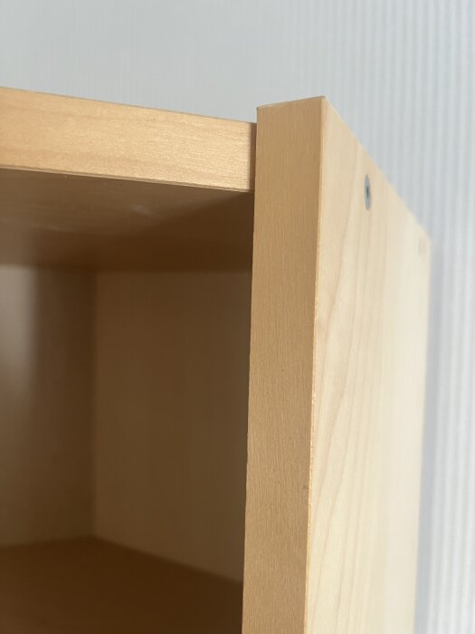 Öppen hörnbokhylla av trä med synlig överkant och sida, del av projekt för att bygga dörr.