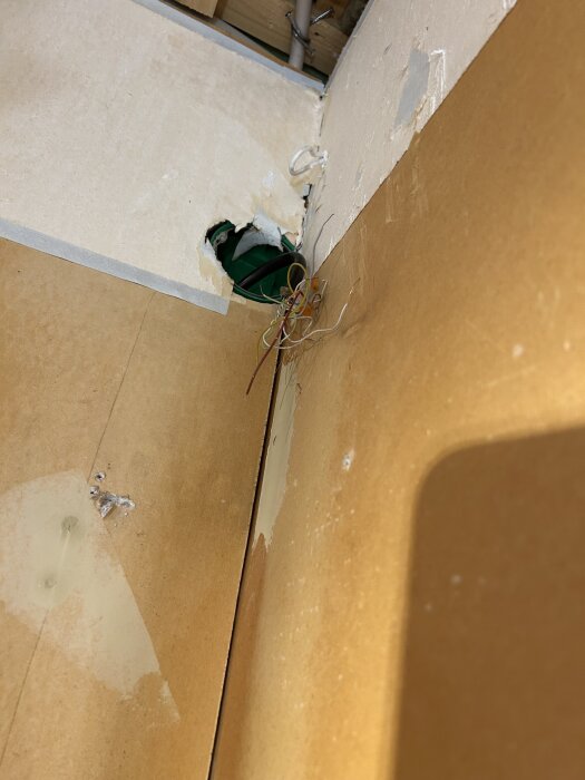 Innerhörn i ett hus byggt av lättklinkerblock med avskalad gips och exponerade kablar, redo för spackling och reparation.