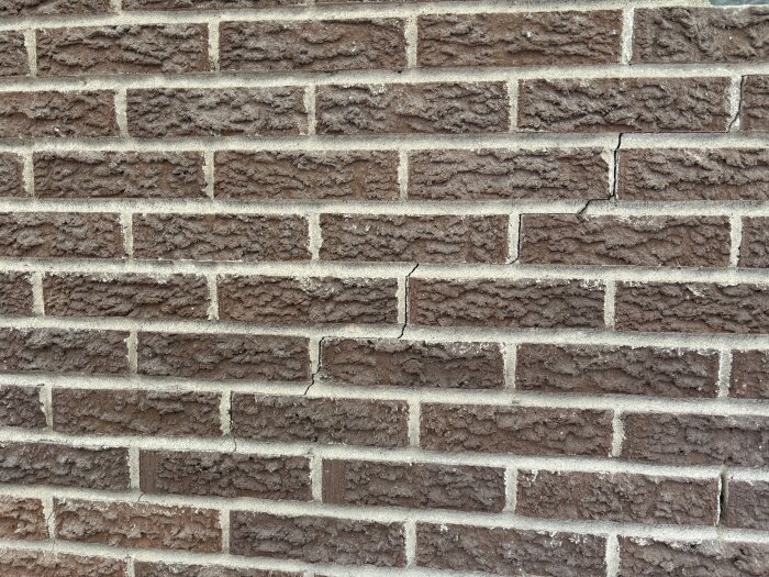 Sprickor i tegelvägg visar skador på murverk.