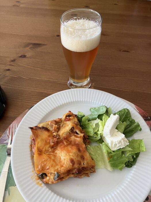 Sydfransk lasagne med lammfärs, zucchini och sallad på en tallrik bredvid ett glas öl.