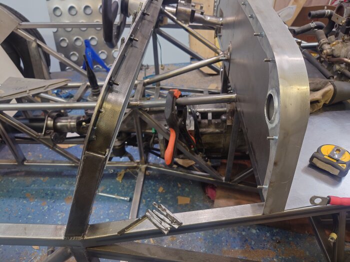 Konstruktion av en bilram i aluminium med verktyg och skruvar synliga på verkstadsgolvet.