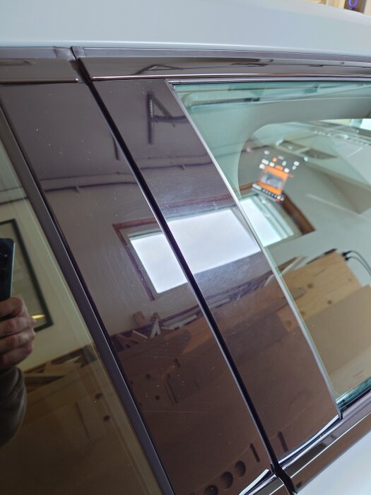 Högblanka lister på dörrar före polering, med reflexioner och synliga smårepiga ytor.